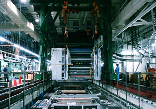工場内の2階に設置した40トン吊りガントリーで、印刷機械（新聞輪転機）の搬入・据付風景。